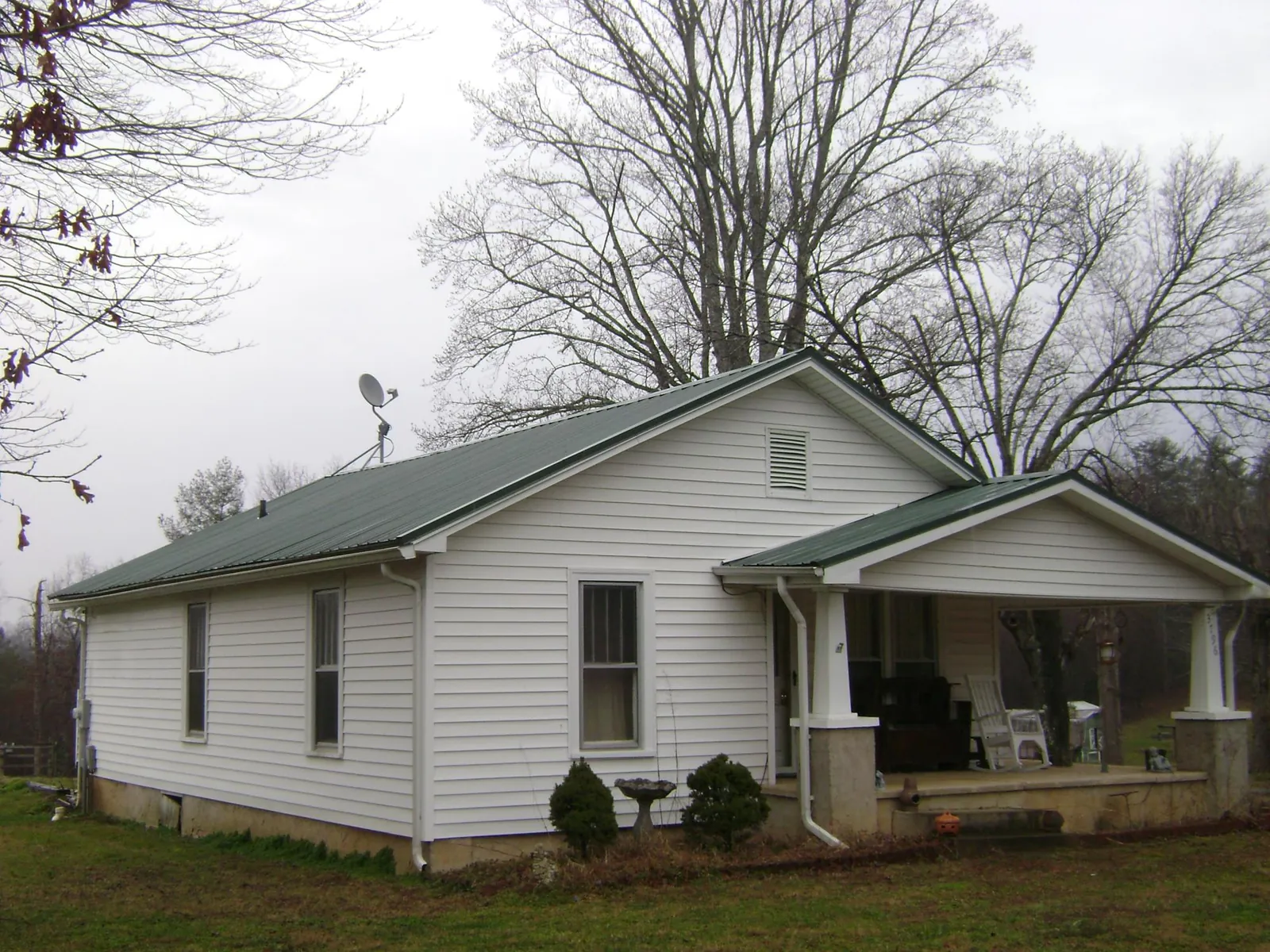 Green metal roof on a white bungalow with a side porch in Van Wert