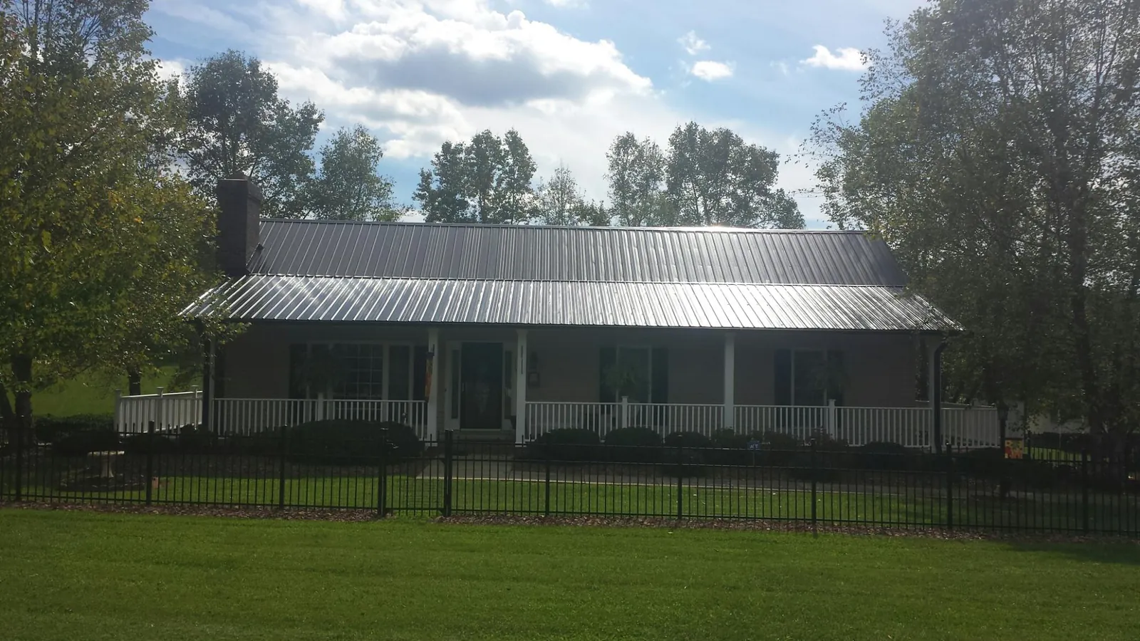 Gray metal roof on a brick ranch with a full width front porch — Gutter Guard Installation work by our crew in Van Wert